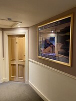 A hallway with a framed picture of Edinburgh, a wooden door, and a carpeted floor.