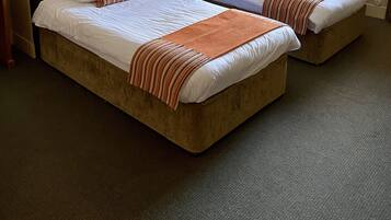 A hotel room with two beds, a ceiling lamp, a nightstand, and a window with curtains.