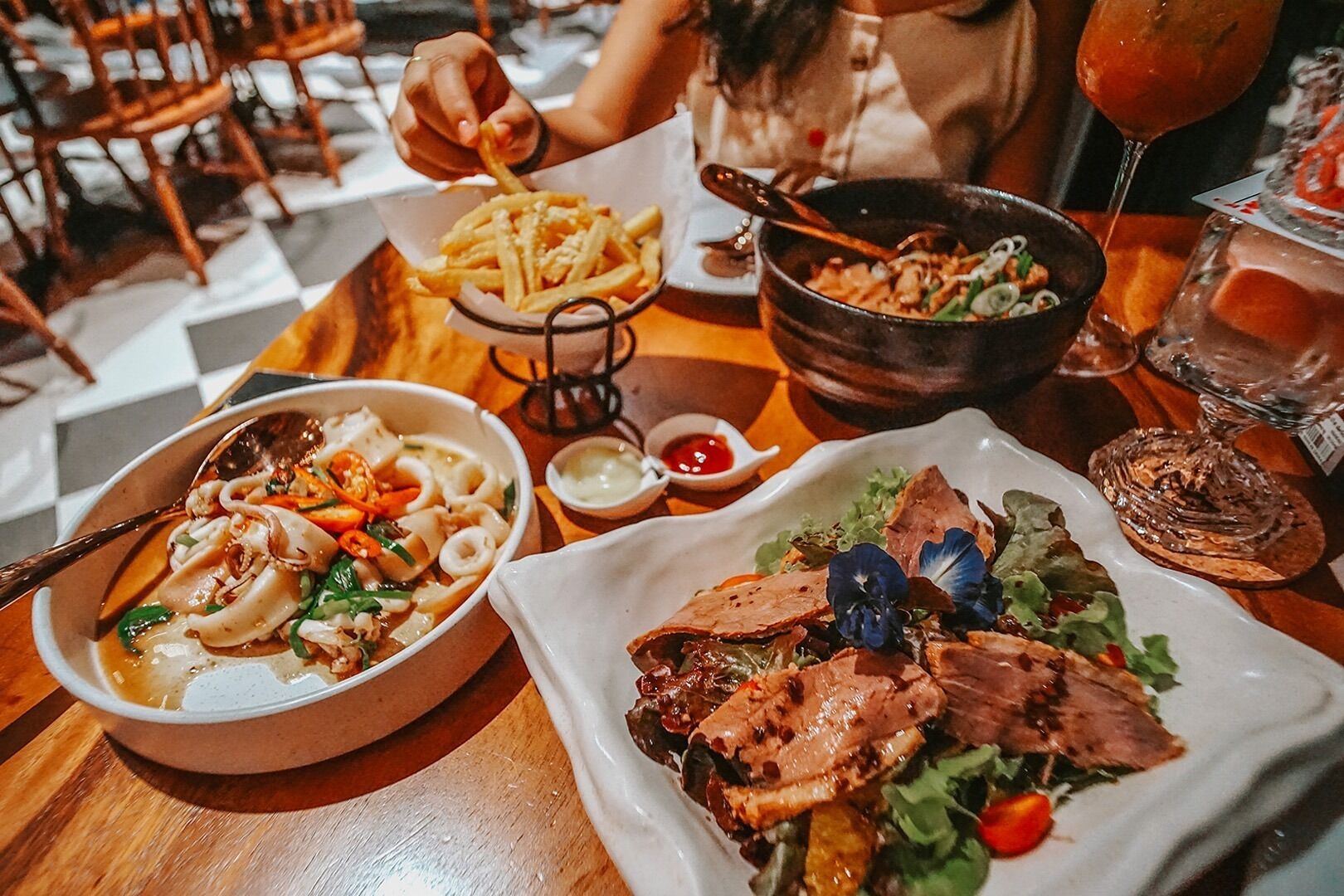 A dining table with various dishes including pasta, a salad, and a bowl of soup.