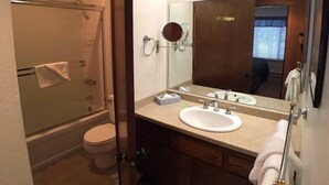 Ein Badezimmer mit Dusche, Toilette, Waschbecken und einem großen Spiegel.