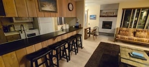 Una cocina con barra, armarios de madera, una mesa de comedor con sillas y un sofá.