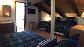 Ein Schlafzimmer mit zwei Betten, einem Fernseher und einem Badezimmer mit einem Waschbecken.