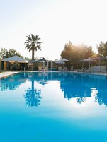 Una piscina al aire libre, sombrillas, sillones reclinables de piscina