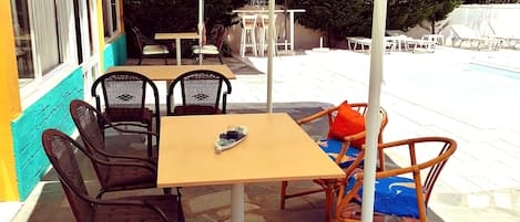 Un patio al aire libre con mesa, sillas, piscina y sombrillas.