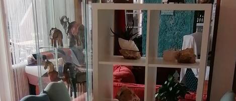 Un comedor con una mesa, sillas, una planta en maceta y una estantería con adornos.