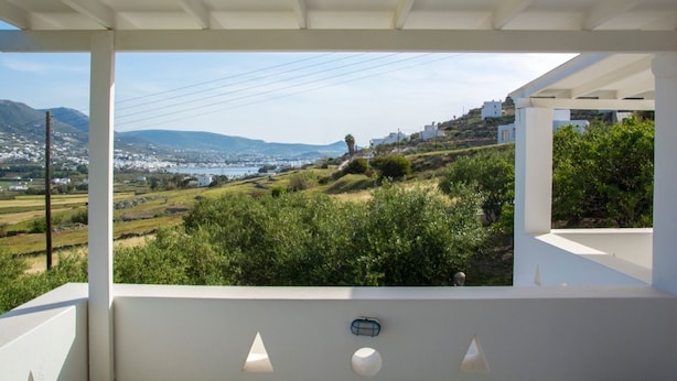 A balcony with a view of a coastal landscape, including hills and a body of water. - Kirki Studios (Paros)