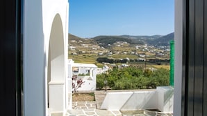 A view from a balcony with a stone floor, white walls, and a green bottle. - Kirki Studios (Paros)
