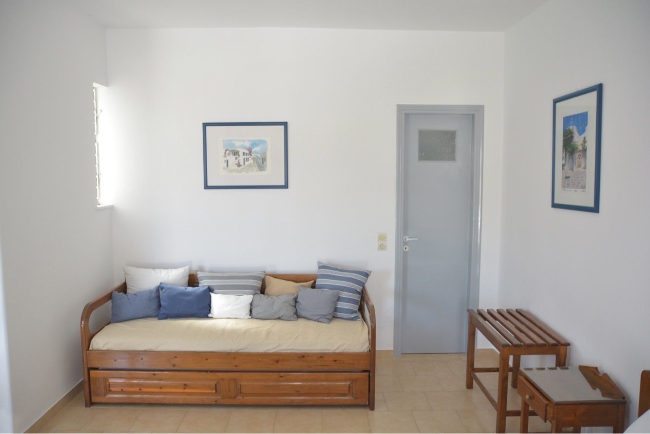 A bedroom with a wooden bed, a small wooden table, and two framed pictures on the wall.
