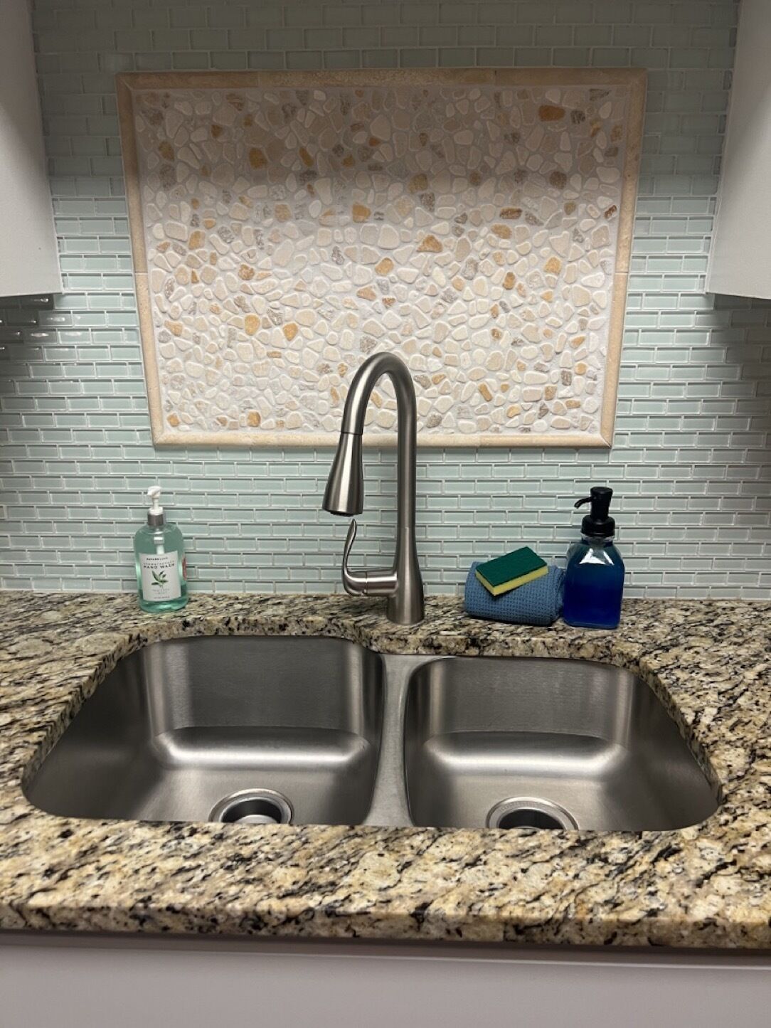 Cocina con pileta doble de acero inoxidable, encimera de granito y un salpicadero decorativo.