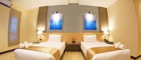 A hotel room with two beds, a large wall-mounted artwork, and a small table with a vase.