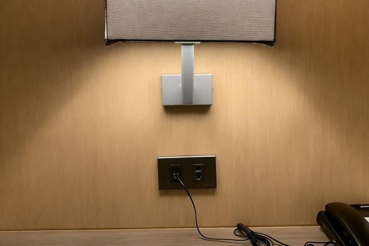 Ein an der Wand montierter Fernseher, eine Steckdose und ein Telefon an einer Holzverkleidung.