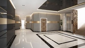 A modern hotel lobby with a central seating area, a reception desk, and a staircase. - ibiz Boutique Hotel (Nakhon Si Thammarat)