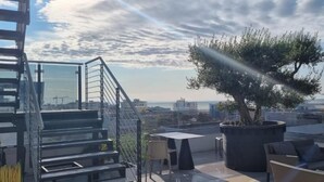 A rooftop terrace with a staircase, seating area, and a large tree. - Hotel Venice Beach (San Michele al Tagliamento)
