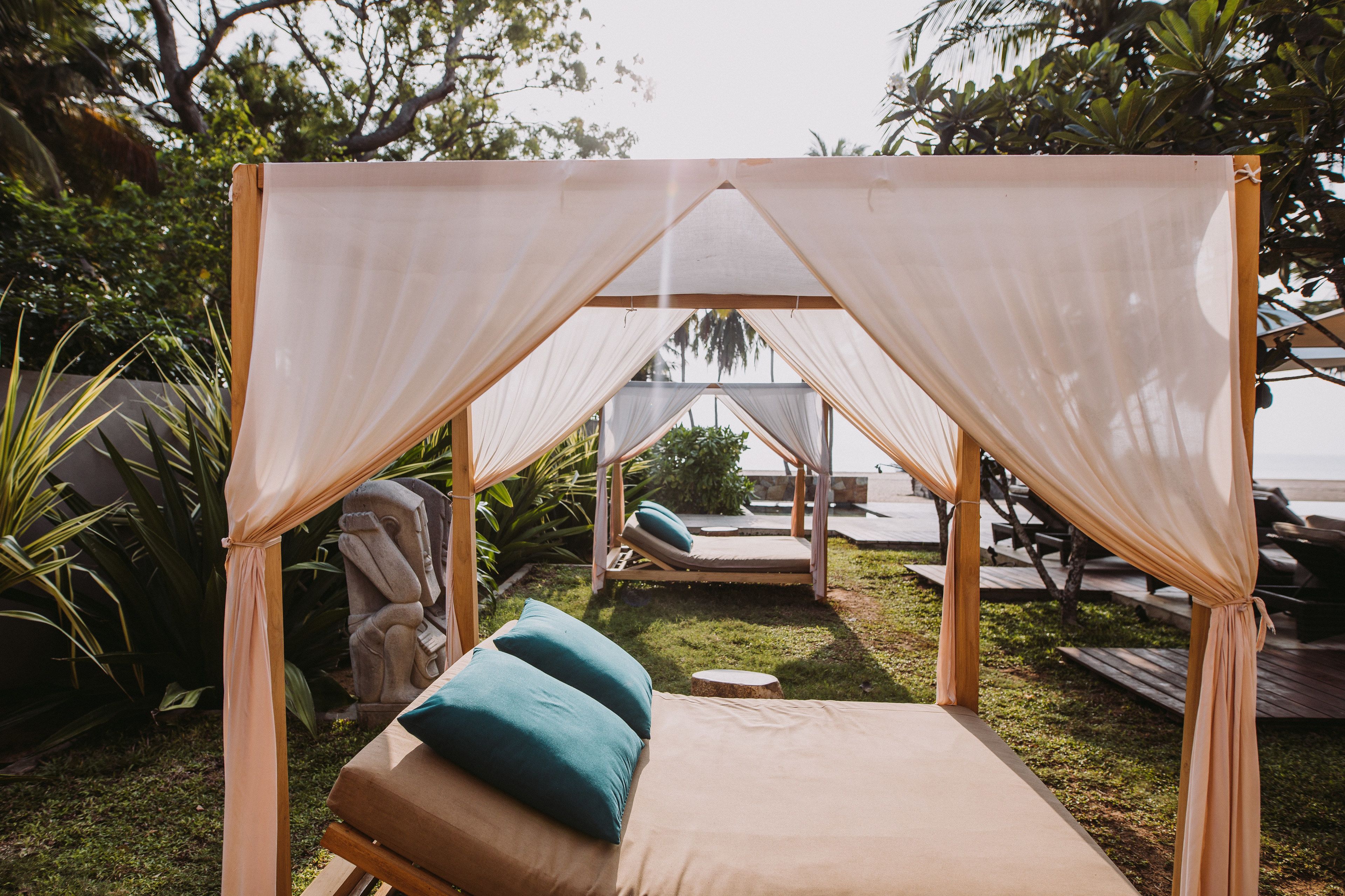 A covered outdoor seating area with a cushioned bench and a canopy.