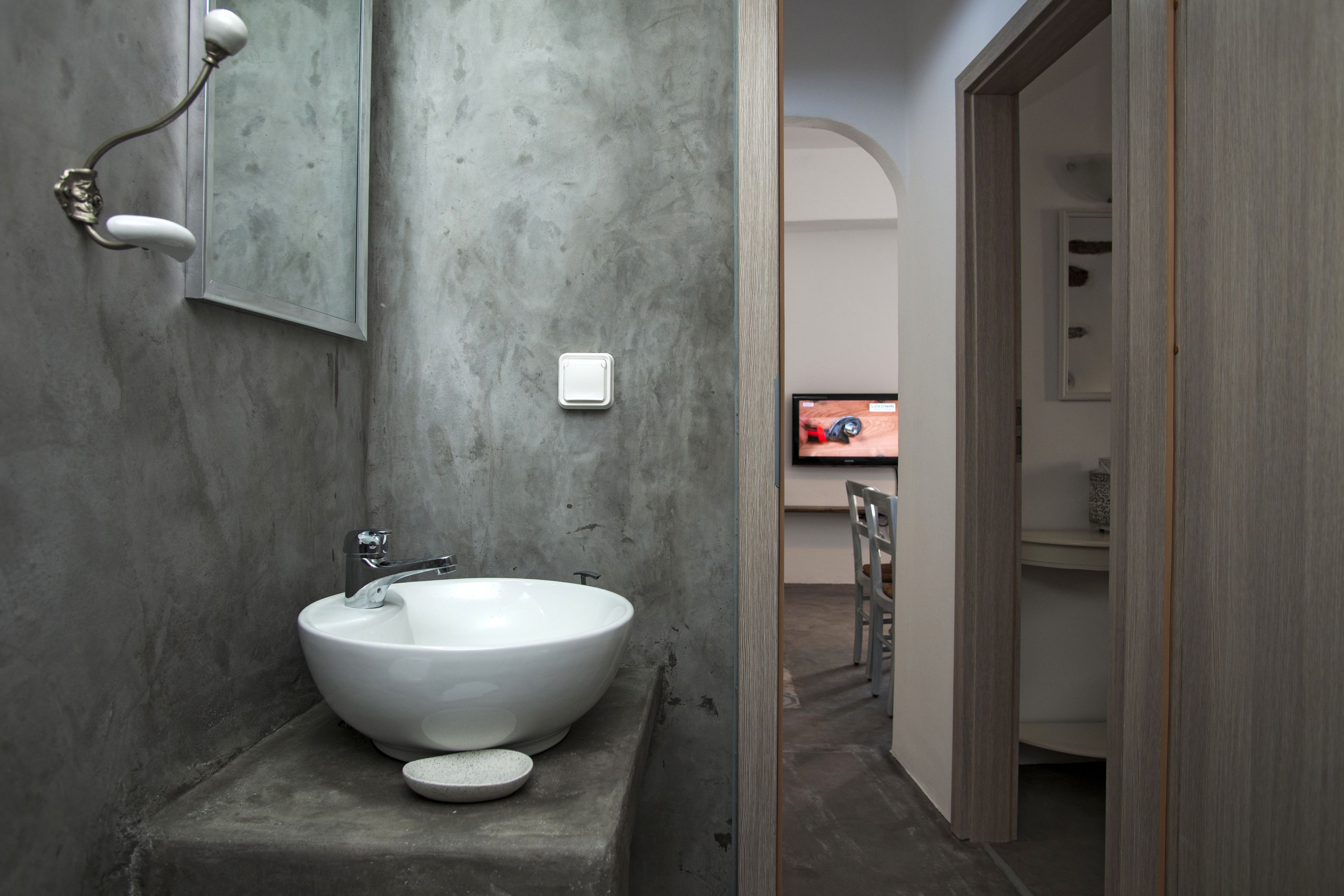 Ein Badezimmer mit einem großen weißen Waschbecken, einem Spiegel und einem Lichtschalter an der Wand.