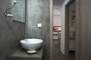 Ein Badezimmer mit einem großen weißen Waschbecken, einem Spiegel und einem Lichtschalter an der Wand.