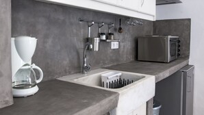 A modern kitchen with a coffee maker, a toaster, and a sink with a dish rack. - Portes View House (Paros)