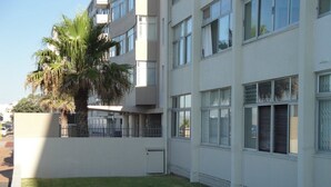A modern building with multiple floors, large windows, and a well-maintained lawn. - Sandringham I (Cape Town)