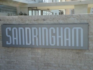 Une plaque portant le nom « SANDRINGHAM » est fixée à un mur de pierre.