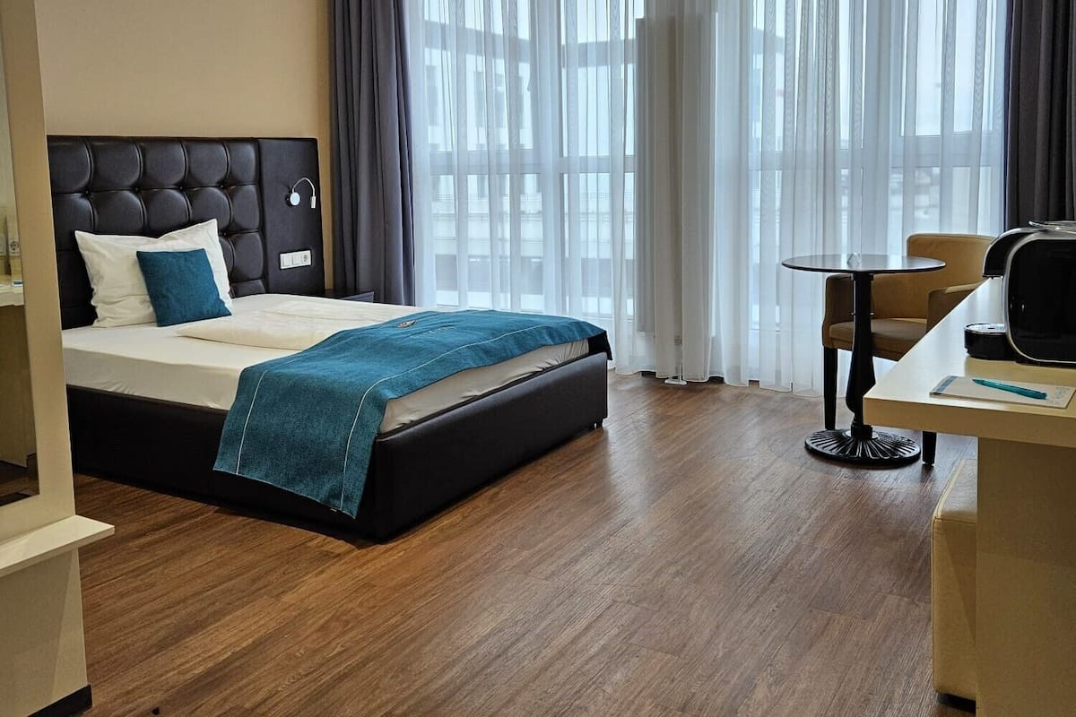 A hotel room with a large bed, a desk, and a chair.