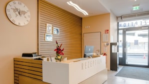 A reception desk with a clock, framed pictures, and a computer. - RheinCity Hotel (Ludwigshafen)