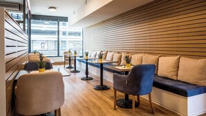 A modern interior with wooden paneling, a seating area with sofas and chairs, and a view through large windows. - RheinCity Hotel (Ludwigshafen)