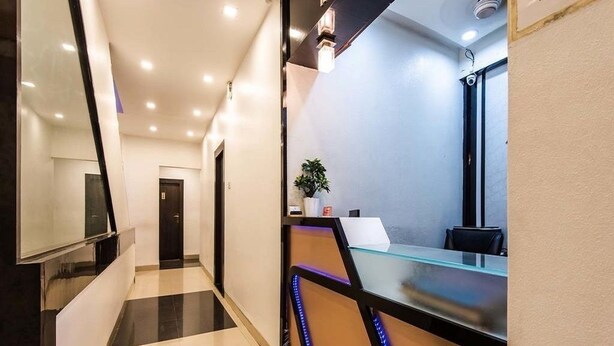 A modern reception area with a glass counter, a potted plant, and a sign above the counter. - Room Maangta 136 - CST (Mumbai)
