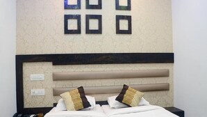 A hotel room with a bed, two bedside tables, a headboard, and wall-mounted light fixtures. - Room Maangta 136 - CST (Mumbai)