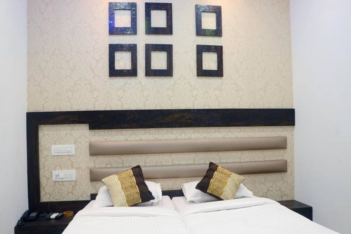 Una habitación de hotel con una cama, dos mesitas de noche, un cabecero e iluminación fijada a la pared.
