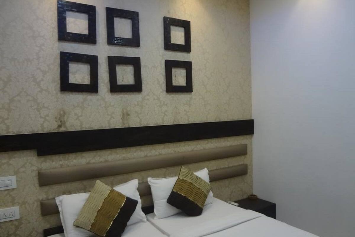 Una habitación de hotel con cama, dos almohadas, cabecero y una pared con cuadros.