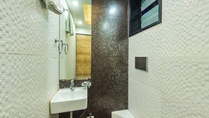 A bathroom with a white sink, a mirror, a dark brown accent wall, and a window. - Room Maangta 136 - CST (Mumbai)