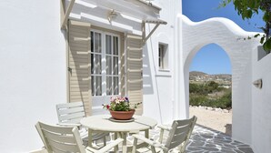 A white building with a stone floor and a white door. - Vagia Calm House (Paros)