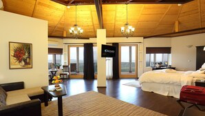 A spacious room with a large bed, a sofa, a dining table with fruit, and a TV. - Seven Generations Winery Hotel & SPA (Ivanovo)