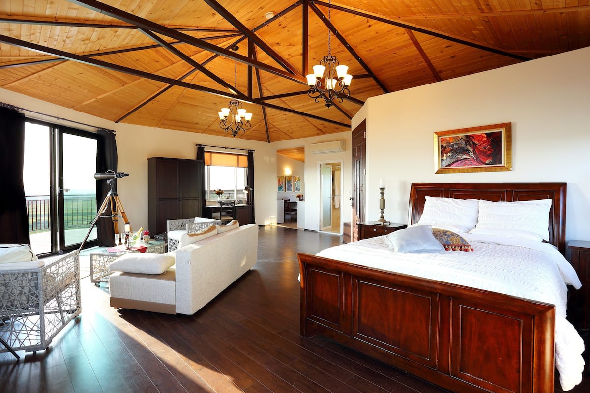 Une chambre spacieuse avec un grand lit, un balcon et une vue sur l’extérieur.
