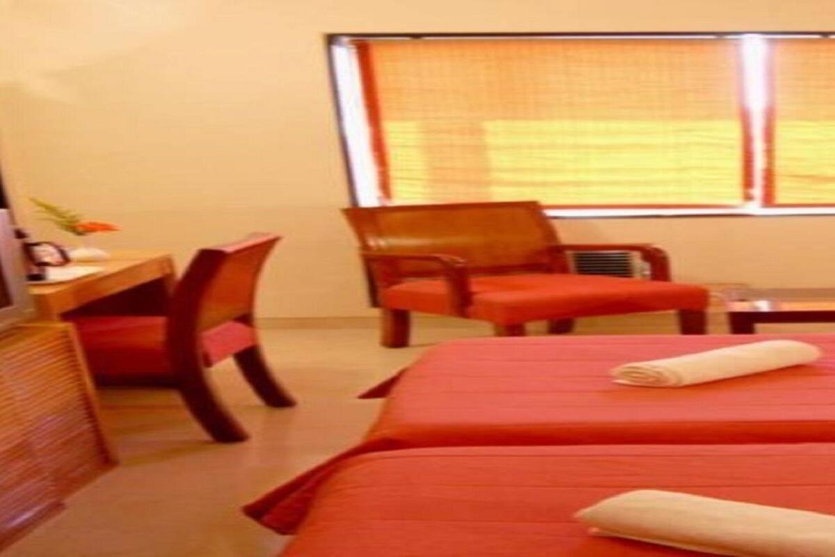 Une chambre d’hôtel avec deux lits, un bureau, une chaise et un téléviseur.