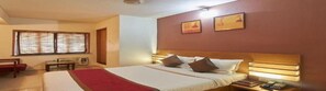 A hotel room with a large bed, a bedside table, a chair, and a window with blinds.
