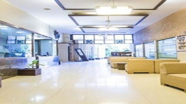 A hotel lobby with a reception desk, seating area, and large windows. - Room Maangta 213 - Juhu (Mumbai)