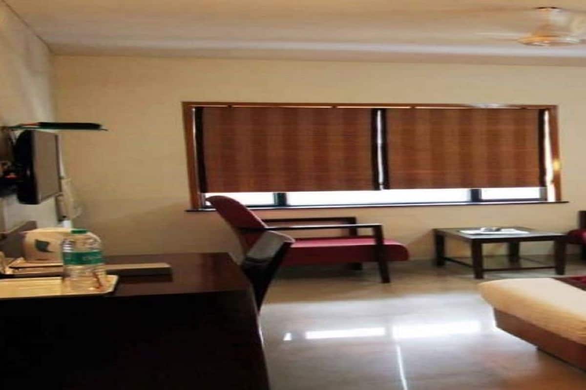 Une chambre d’hôtel équipée d’un lit, d’un bureau, d’une chaise, d’une table et d’une fenêtre avec des stores.