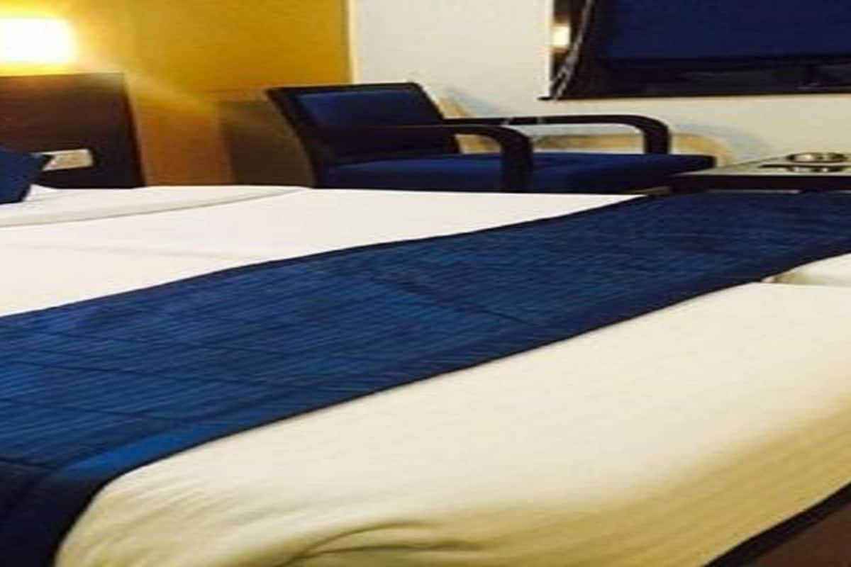 Un lit double avec une literie blanche et bleue, un plaid bleu et une tête de lit agrémentée de deux coussins bleus.