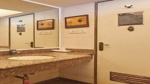 A bathroom with a granite countertop sink, a mirror, and a door with a vent. - Room Maangta 213 - Juhu (Mumbai)