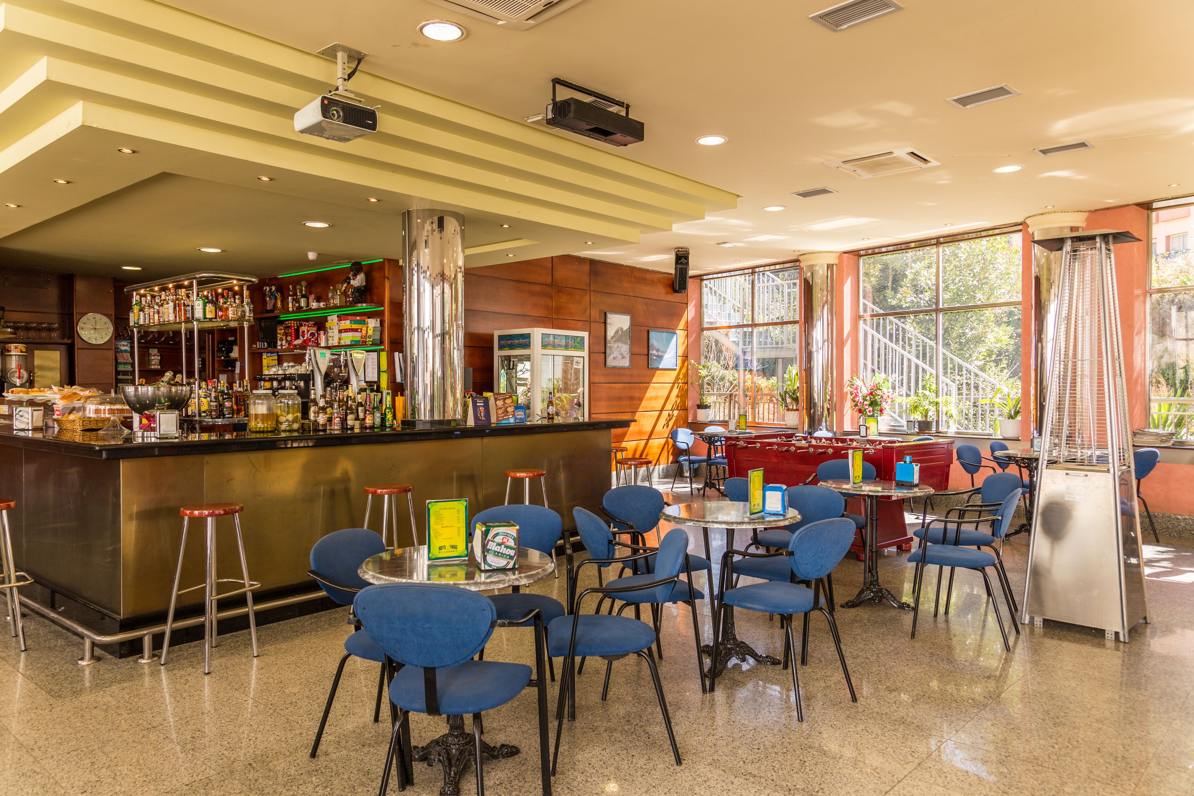 A bar area with stools, tables, and a counter with various bottles.