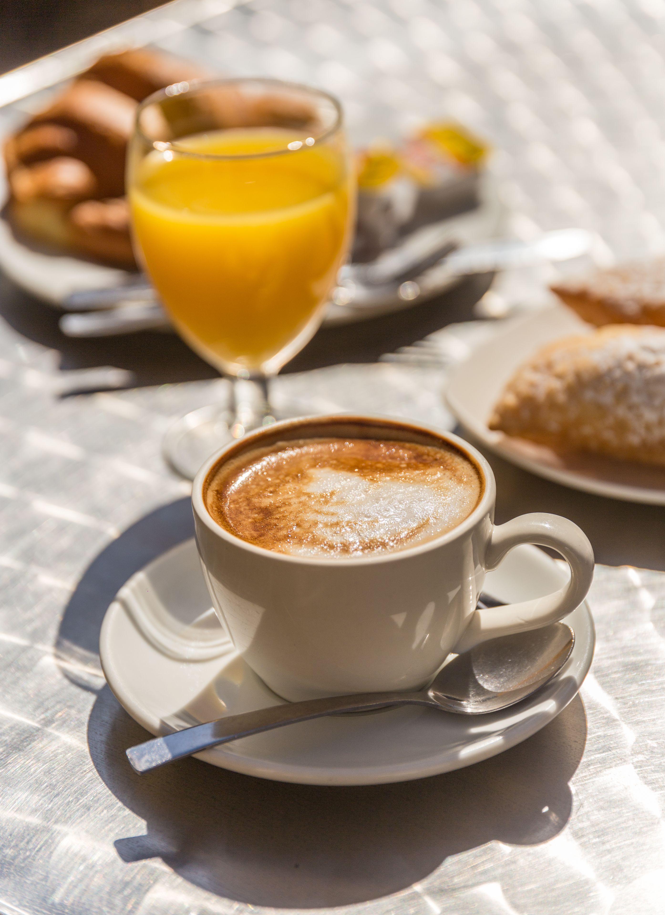 A cup of coffee with a saucer and spoon on a table.