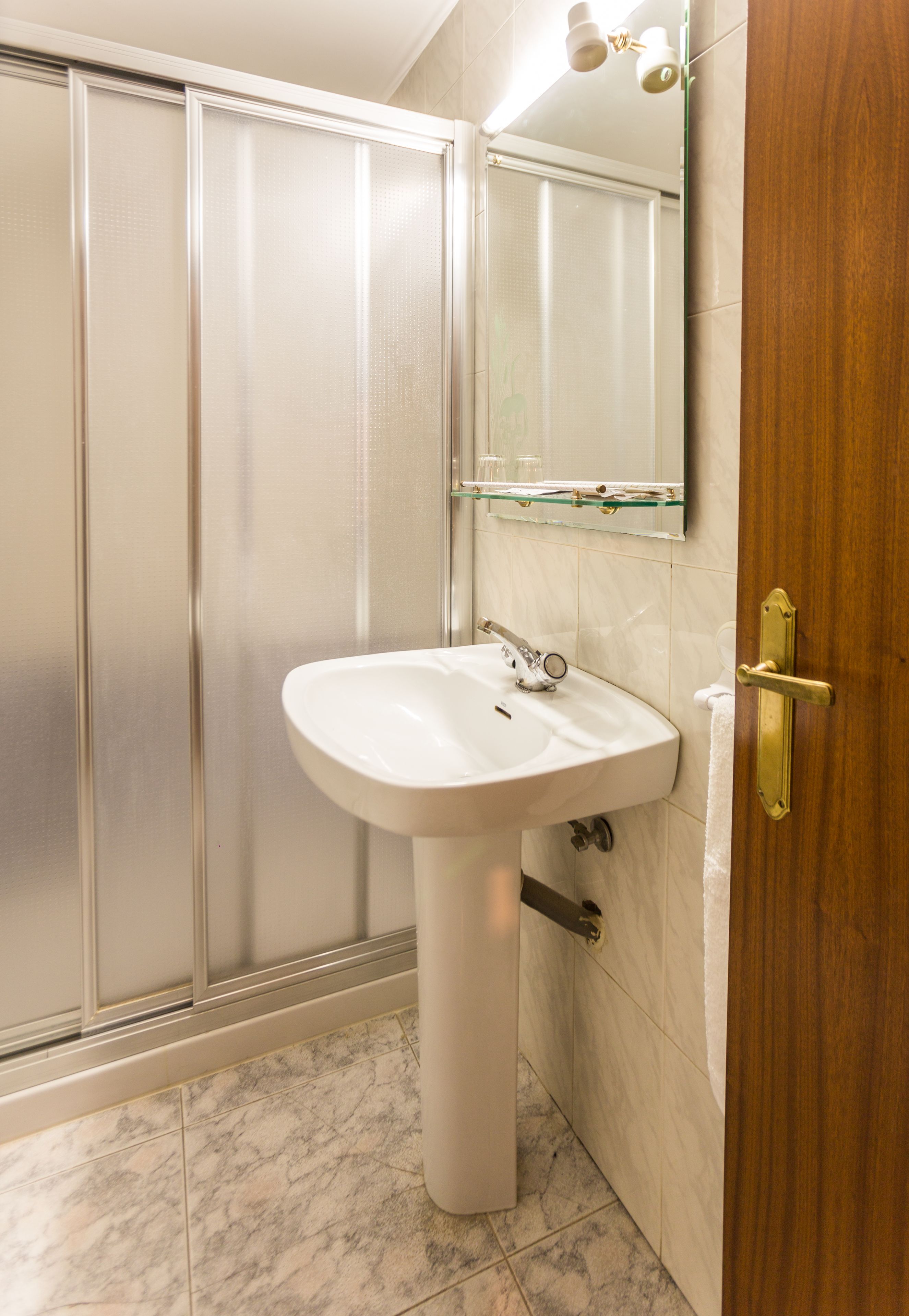 Un baño con ducha, lavamanos y espejo.