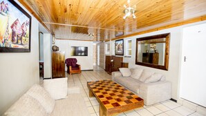 A living room with a wooden ceiling, a checkered coffee table, a sofa, and a TV.