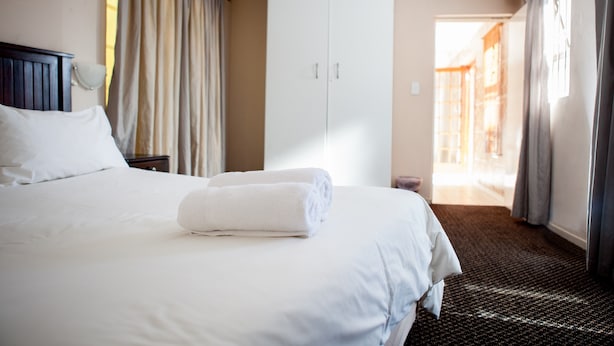 A hotel room with a bed, a wardrobe, and a view of the outside.