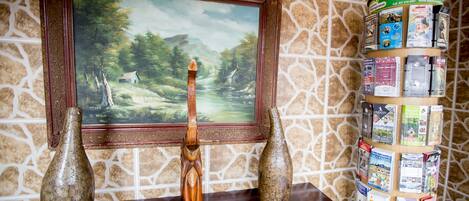 Una mesa de madera con un cuadro enmarco, dos jarrones y un expositor de folletos.