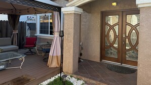 A covered patio with outdoor furniture, a door with decorative glass panels, and a stone-tiled entrance. - Large Gorgeous home! Can sleep large groups (Long Beach)