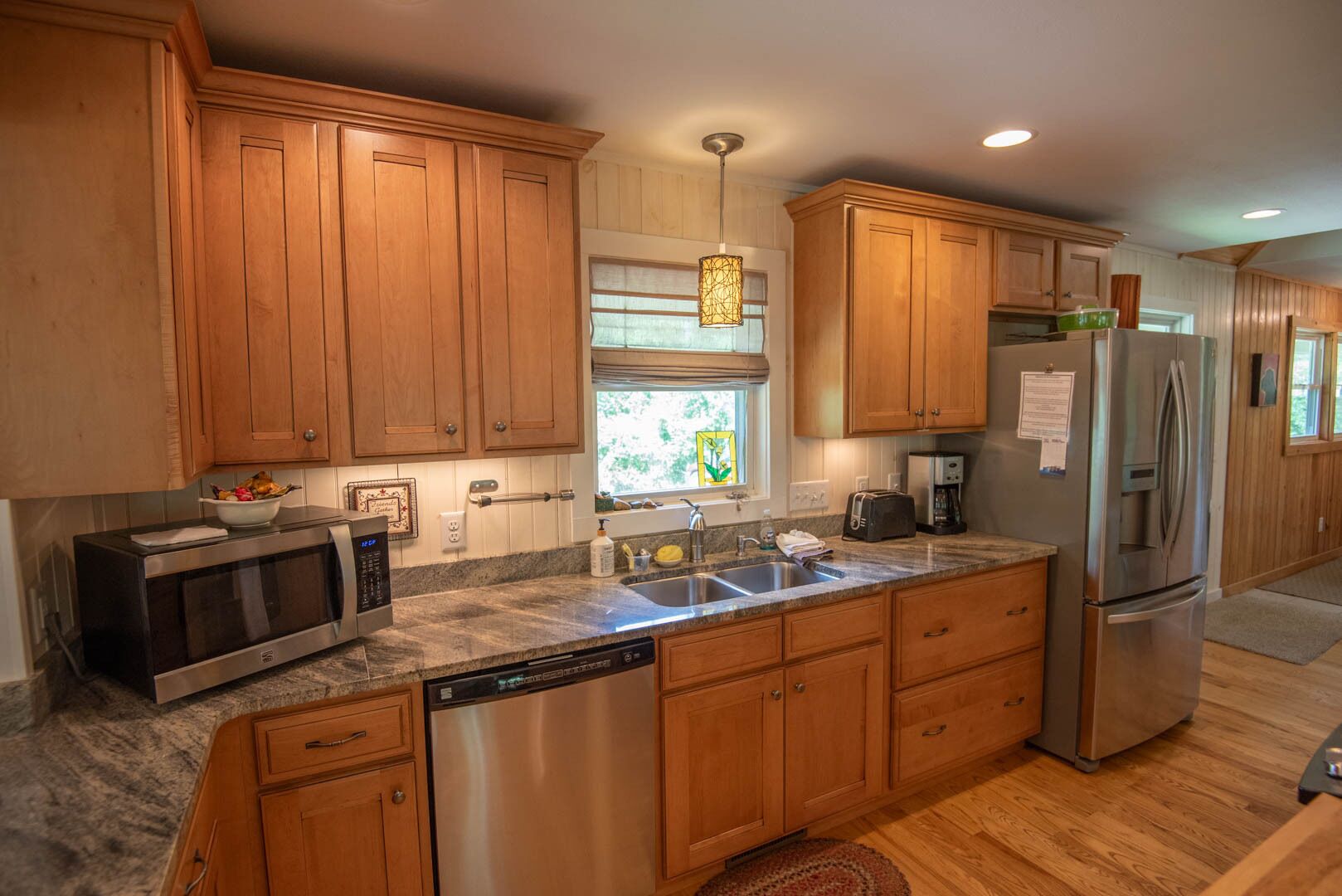 A modern kitchen with wooden cabinets, stainless steel appliances, and a granite countertop.