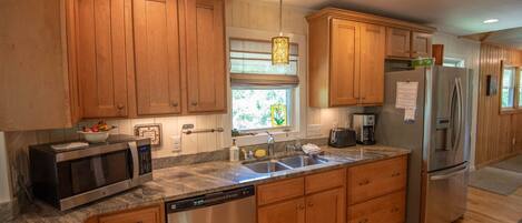 A modern kitchen with wooden cabinets, stainless steel appliances, and a granite countertop.
