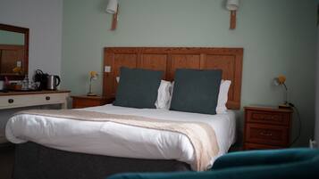 A bedroom with a wooden headboard, two bedside lamps, a bed with white bedding, and a nightstand with a lamp.